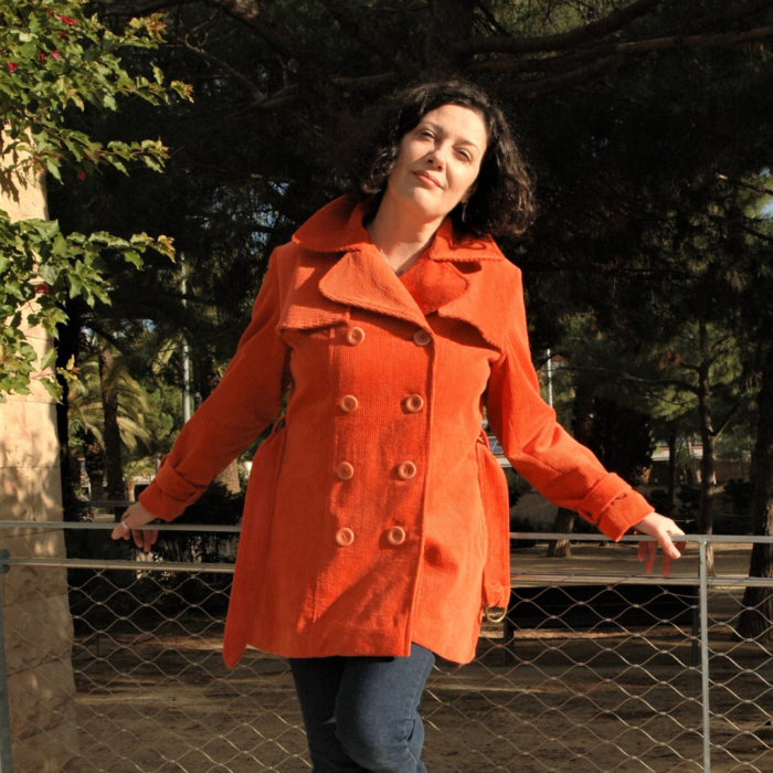 Mujer con la Gabardina Gal·la de La Nina de Paper color naranja apoyada en un parque